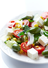 Healthy Salad with Feta Cheese, Green Olives, Baby Spinach, Cucumber, Cherry Tomatoes and Capers. Bright background. Close up.