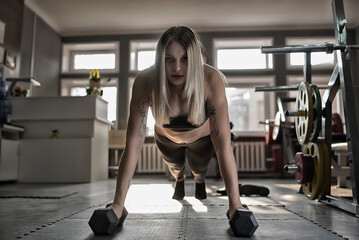 Obraz na płótnie Canvas Young beautiful girl athlete does push-ups in the fitness room.