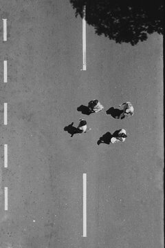 Black and white photo of four persons jaywalking