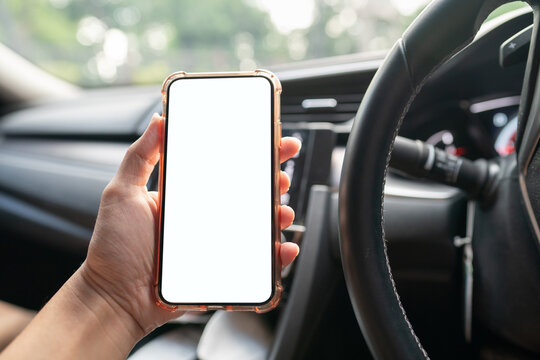 Image of hand holding mobile phone with mockup white screen in car.