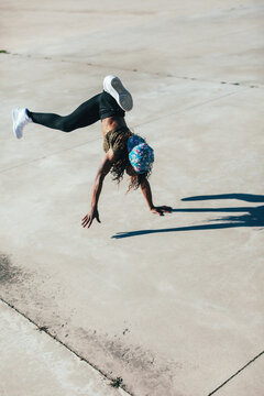 Young african american woman performing break dance in a city.