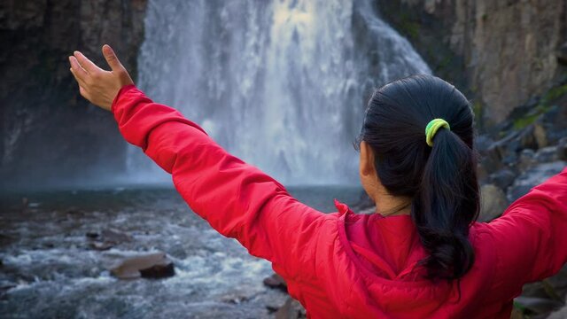 Asian woman enjoying the beautiful Rainbow Falls in the Ansel Adams Wilderness near Mammoth Lakes California USA