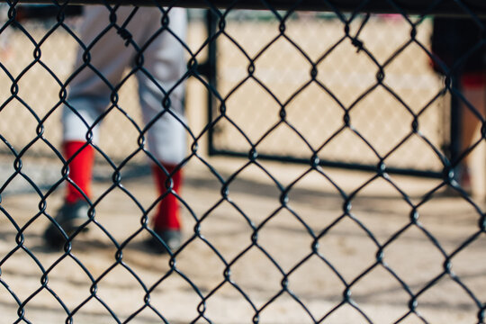 Junior baseball player legs through a wire fence