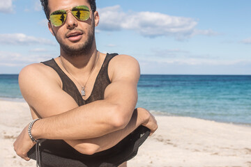 handsome young man get undressed on a sunny beach near the sea