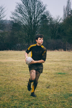 A teenage rugby player running with the ball