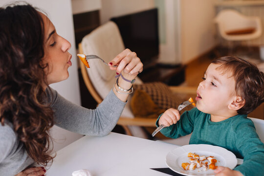 Mother and son eating chicken nuggets for lunch at home.