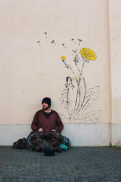 Portrait of young homeless man panhandling on the sidewalk