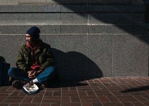 Portrait of older, native homeless man panhandling on the sidewalk