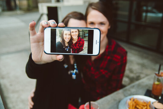 A lesbian couple taking a selfie at brunch