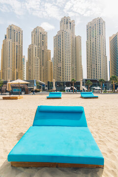 Blue sunbed on the beach and city buildings on the background. Marina Beach, Dubai, United Arab Emirates