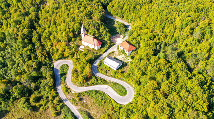 KOSINJ, CROATIA - september 2020 - Aerial view of winding curvy rural road through the forest and village
