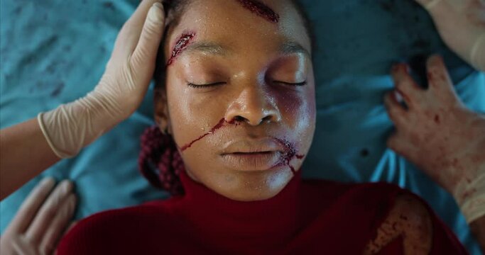 Top view of paramedics transportating afro american woman with blood and head traumas in ambulance. Close up of girl mumbling while lying on medical stretcher on way to hospital