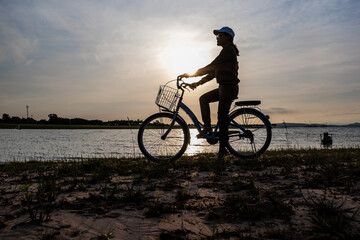 Silhouette of women with vintage bicycle near the beach during sunrise.