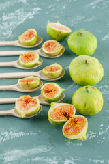 Green figs in wooden spoons on a plaster background. high angle view.