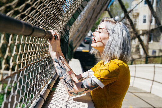 portrait of urban young female in city next to chain link fence