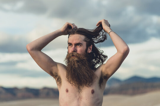 A handsome bearded man with his dogs in beautiful desert hot springs during the golden hour