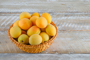 Apricots in a wicker basket on a wooden background. high angle view.