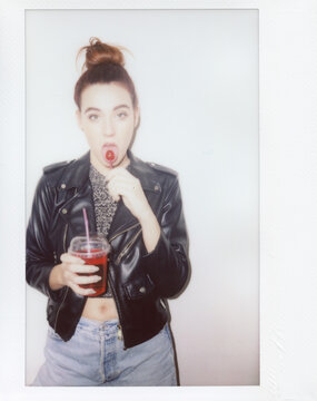 Young woman eating chupa chups and holding drink