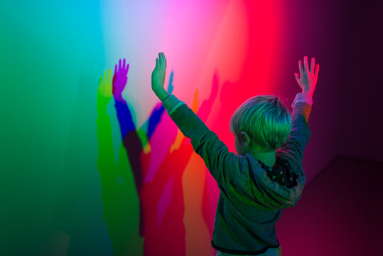 Boy Playing Making Shadows With Colorful Spectrum Multi Color Theatre Lights - Powered by Adobe