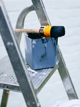 Ladder with paintbrush and paint bucket
