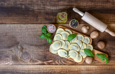 Top view of fresh raw italian filled pasta ravioli or tortelli with mushrooms, pesto, and ricotta. Vegetarian recipe.