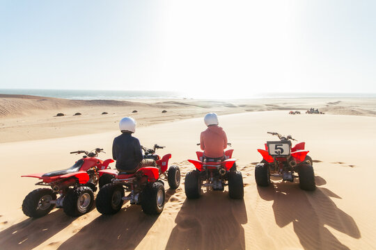 Two people sitting on quad bikes and looking at beautiful landscape