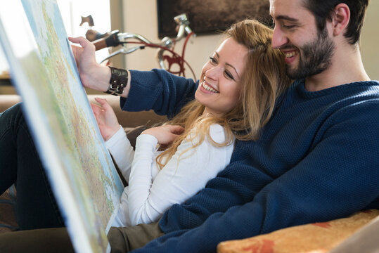 Young couple watching maps for holidays together at home