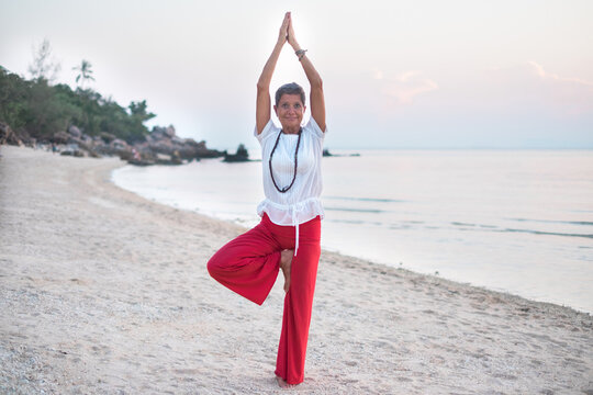 Senior Woman Standing in Yoga Tree Pose at the Beach