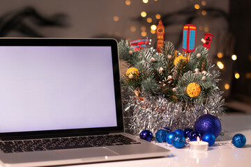 Fototapeta na wymiar laptop with a white screen next to a candle near New Year's decorations. christmas theme. template. 
