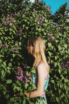 Beautiful young blonde woman standing in a flowering spring garden