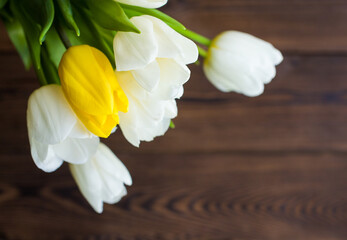 The bouquet of tulips lies on a wooden table. Beautiful bouquet of white and yellow tulips. Close up 