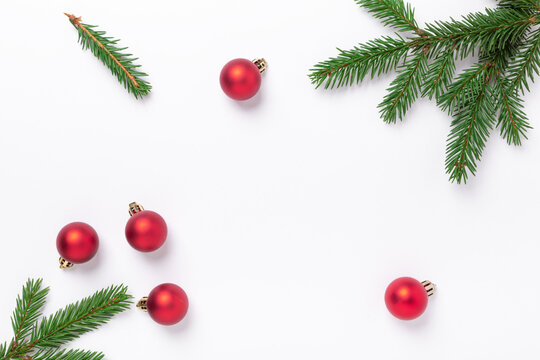 Minimal christmas composition. Fir tree branches with red christmas balls on white background. Top view. Copy space
