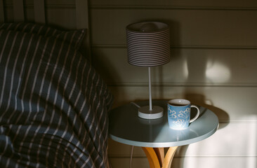 A cup of tea on a bedside table in a blue themed bedroom