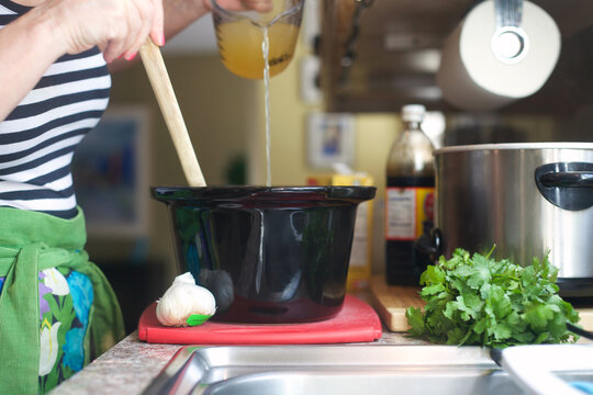 Woman pouring ingredients into a slow cooker