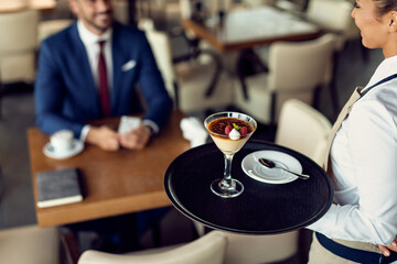 Happy waitress serving lemon tart with raspberry sorbet in a cafe.
