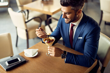 Smiling businessman enjoying in a sorbet for dessert in a cafe.