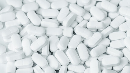Medical background of many white capsule tablets or pills on the table. Full frame background....