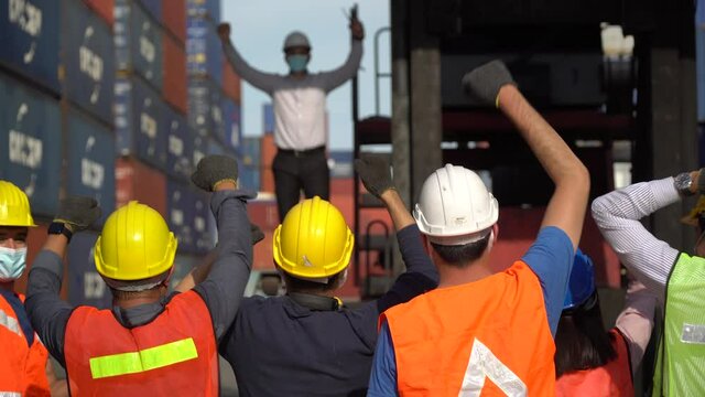 Workers protest in Cargo freight ship for import export logistic During corona virus or covid 19 outbreak . Group of protestors fists raised up in the air . Strike of labor in industry