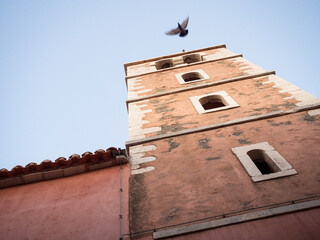 Fototapeta na wymiar Dove flying from a bell tower at Rab in croatia