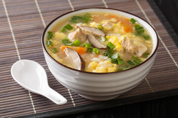Japanese hot Rice Soup Zosui with chicken, egg and vegetables close-up in a bowl on the table. Horizontal