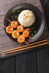 Garlicky and buttery, this simple Japanese Garlic Fried Rice topped with garlic chips with fried shrimps close-up in a plate on the table. Vertical top view from above