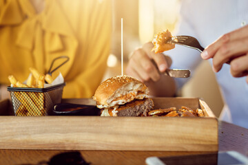 Close-up of man eating cheeseburger on a lunch with his girlfriend.