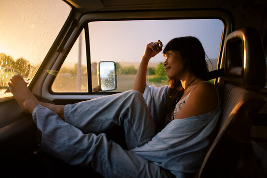 Asian young woman enjoying sunset in the front seat of the camper van