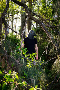 A caucasian man in the woods with crow raven mask on