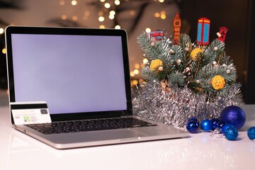 laptop with white screen and credit card near New Year's decorations. Christmas shopping theme. template.