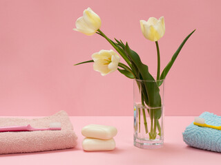 Obraz na płótnie Canvas Bouquet of yellow tulips in vase with towels on a pink background.