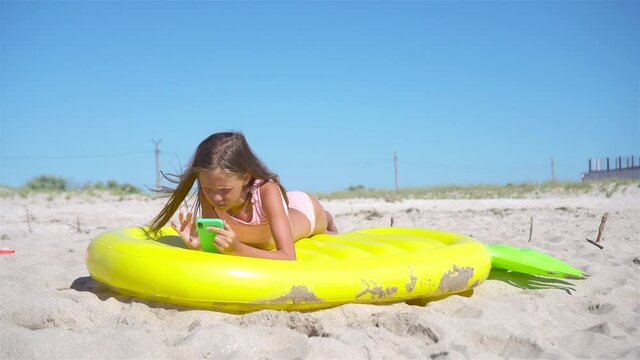 Adorable girl on inflatable air mattress on the beach