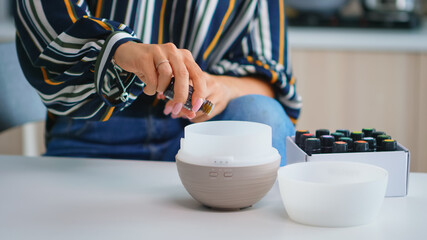 Close up of woman adding essential oils into diffuser. Aroma health essence, welness aromatherapy...