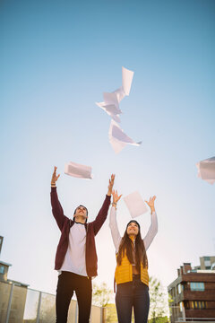 Cheerful Teenager Couple Throwing Class Notes in the Air