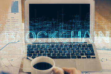 Double exposure of blockchain theme hologram and table with computer background. Concept of bitcoin crypto currency.